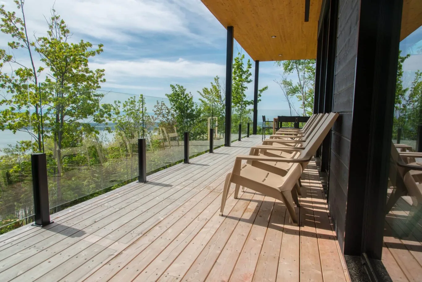 Une rangée de chaises adirondack offrant une vue intacte grâce à une rampe de terrasse en verre