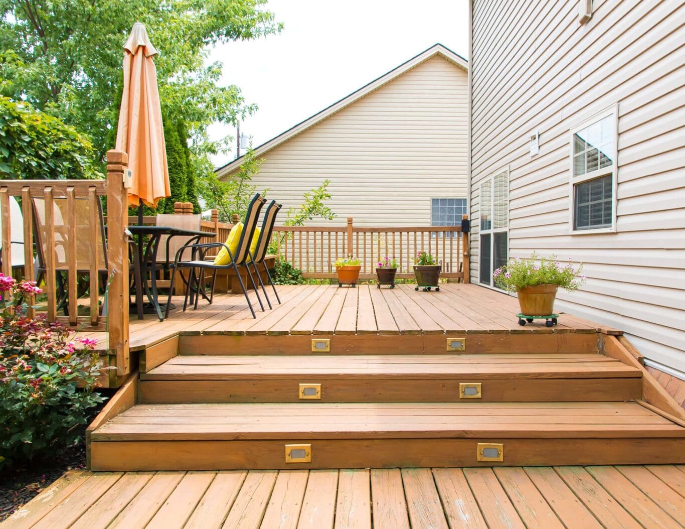 Summer view of a family home deck with three wide deck stairs.